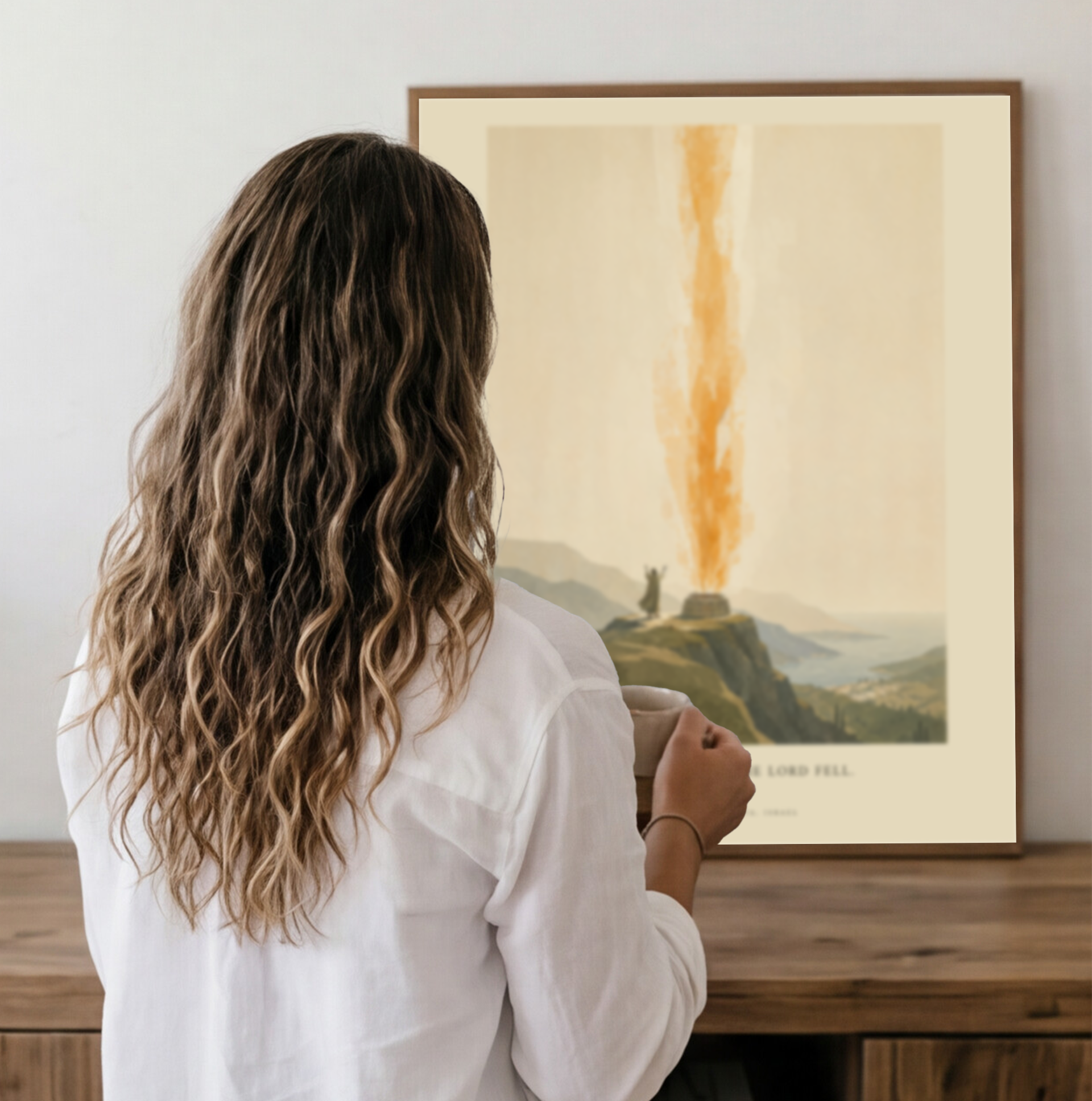 Woman in a white shirt looking at a framed artwork on a wooden surface.