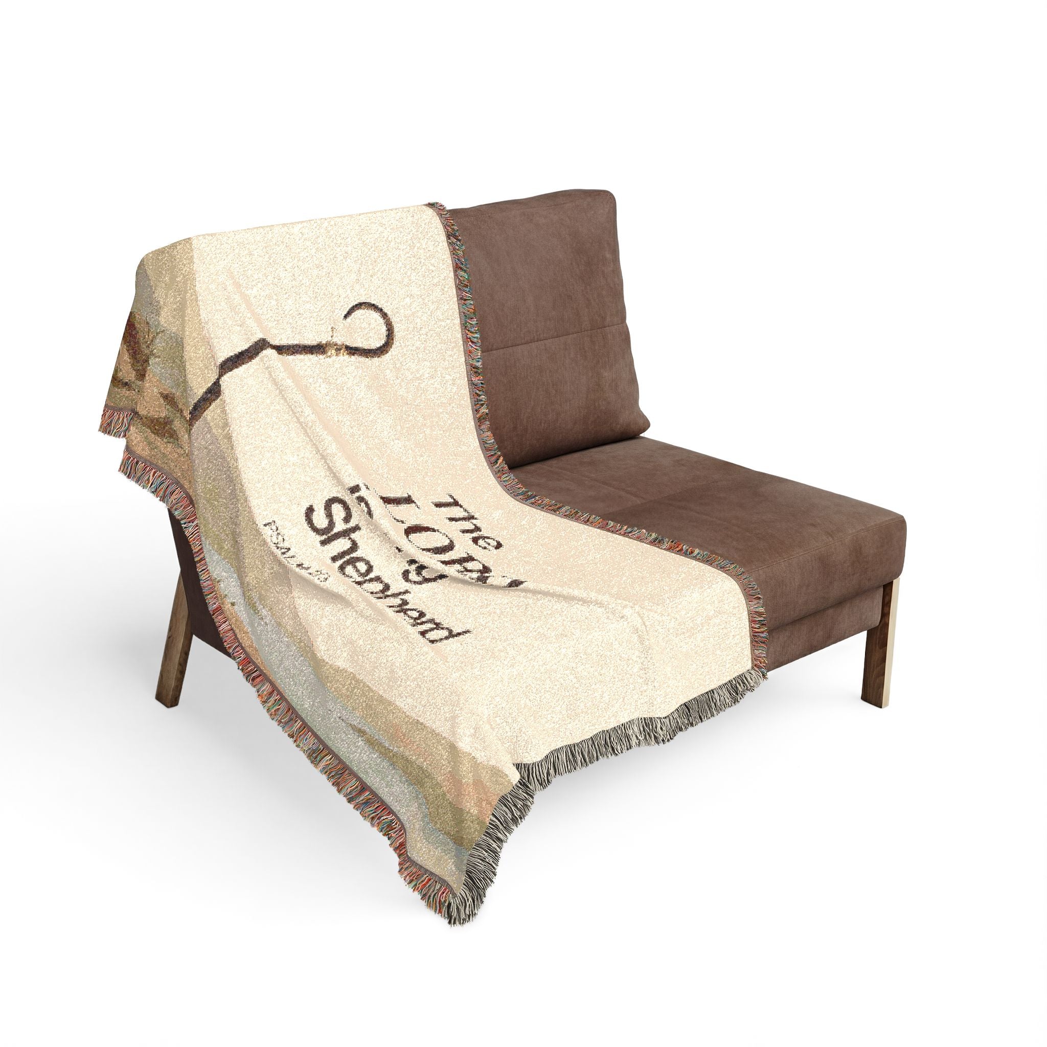 A cream and brown throw blanket with fringe and a printed design of a lasso and the text 'The Lasso of Sheboygan', draped over a brown armchair on a white background.
