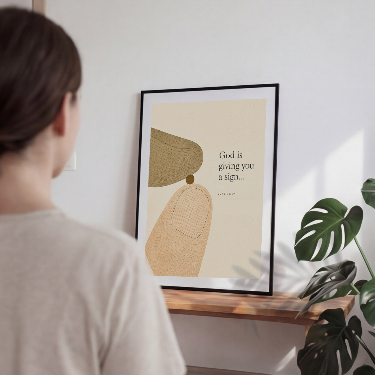 A framed art print featuring minimalist abstract shapes and a Bible verse from Luke 1:39 on a warm cream background, enclosed in a white mat and a thin gold frame.