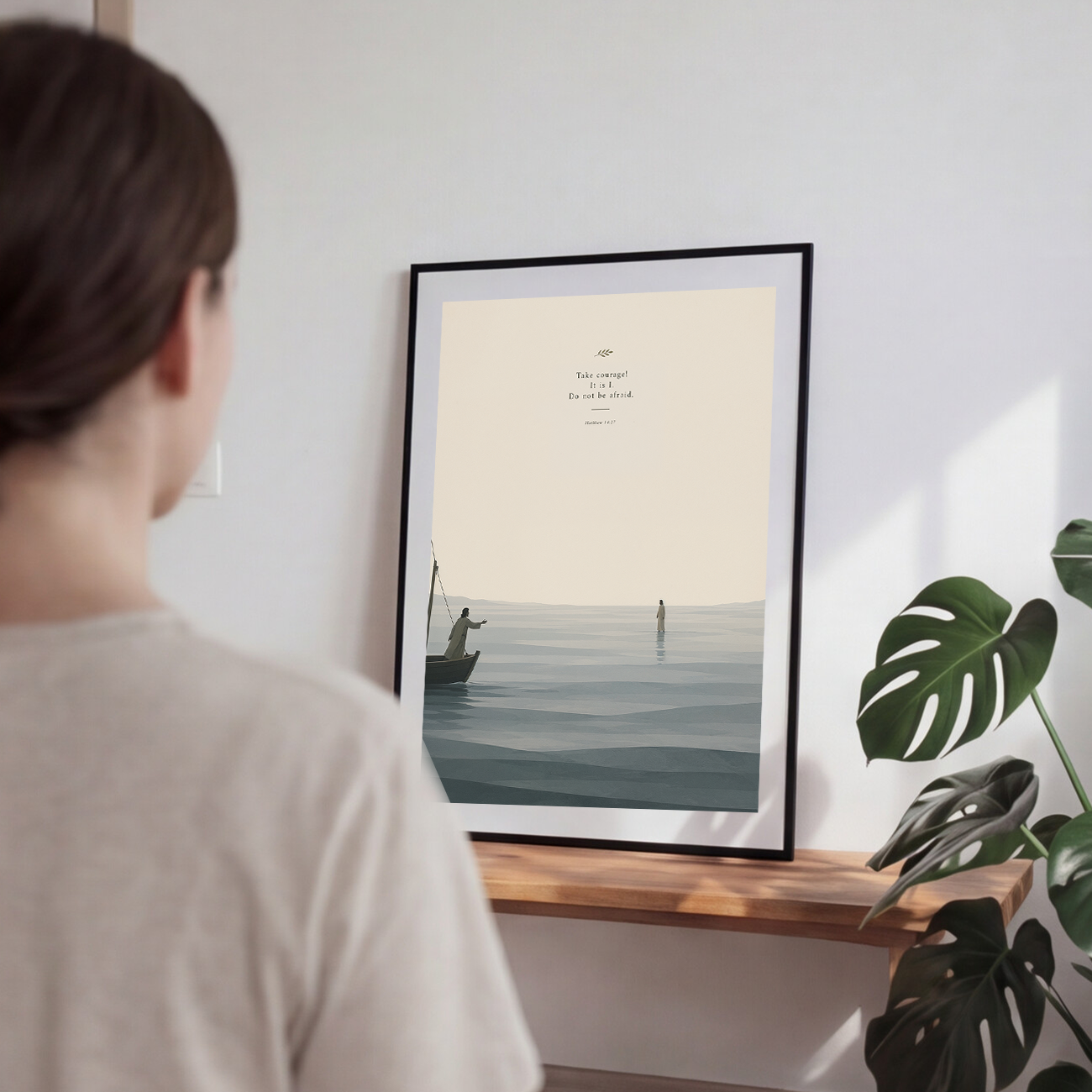 Person looking at a framed artwork of a boat on water with text on a wall.